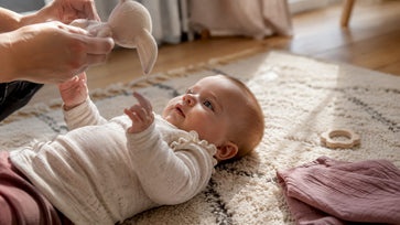 Ouder beweegt een rammelaar bij de baby