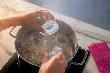 Ouder gebruikt heet water om flesonderdelen te steriliseren
