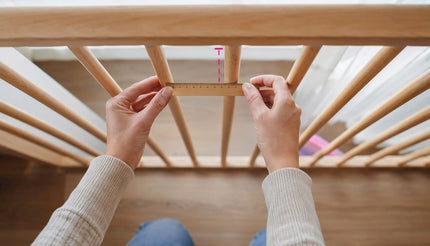 Ouder meet de afstand tussen de spijlen van het ledikant